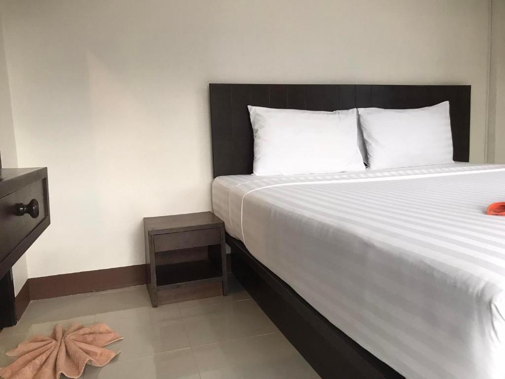 a bedroom with a large white bed with a black headboard at Hassana Apartment in Krabi town