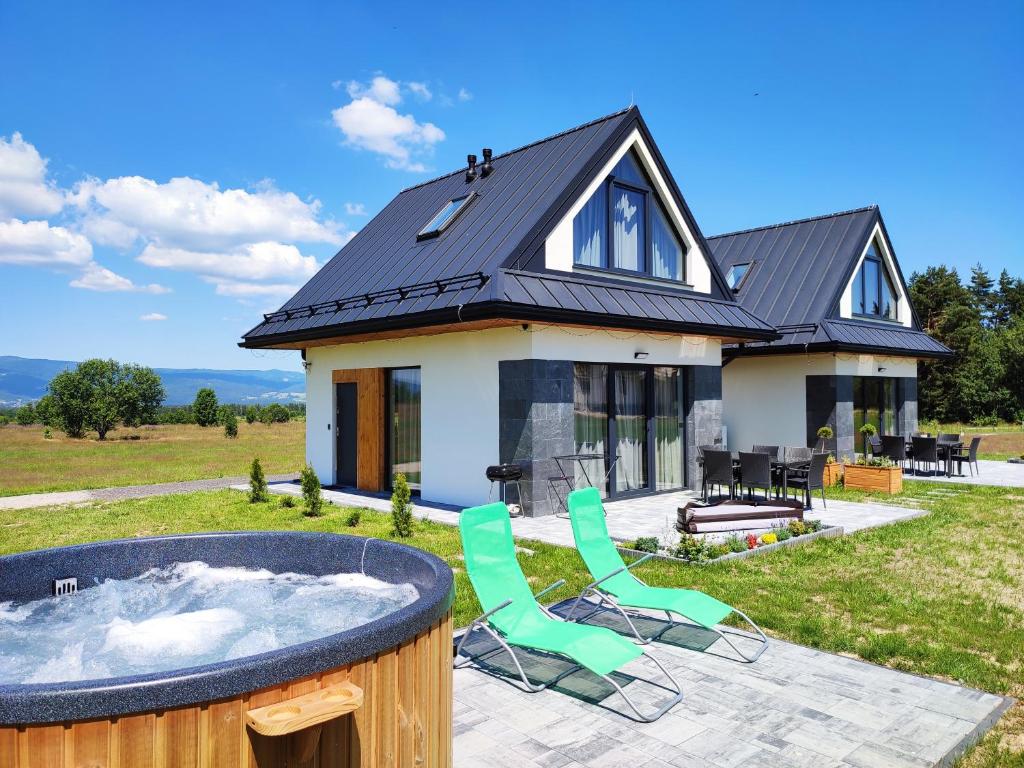 a house with a hot tub and two chairs at Białka i Skałka domki z balia i widokiem na góry in Białka Tatrzańska