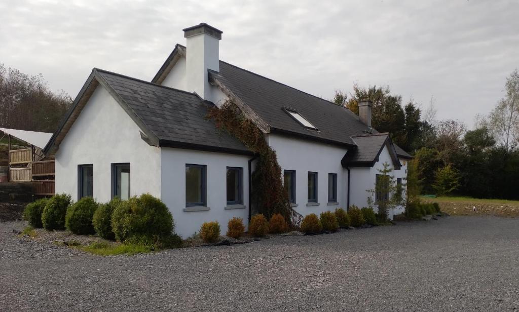 a white house with a black roof at Cornacarta Holiday House in Boyle