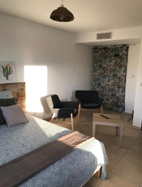 une chambre avec un lit, deux chaises et une table dans l'établissement Studio Benvengudo Port La Ciotat - Appartement et parking, à La Ciotat
