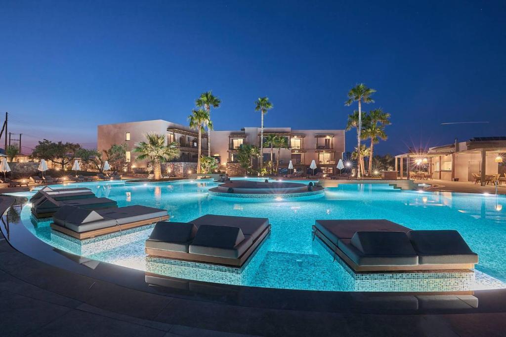 a large swimming pool with chaise lounges in it at night at Sentido Amounda Bay in Amoudara Herakliou