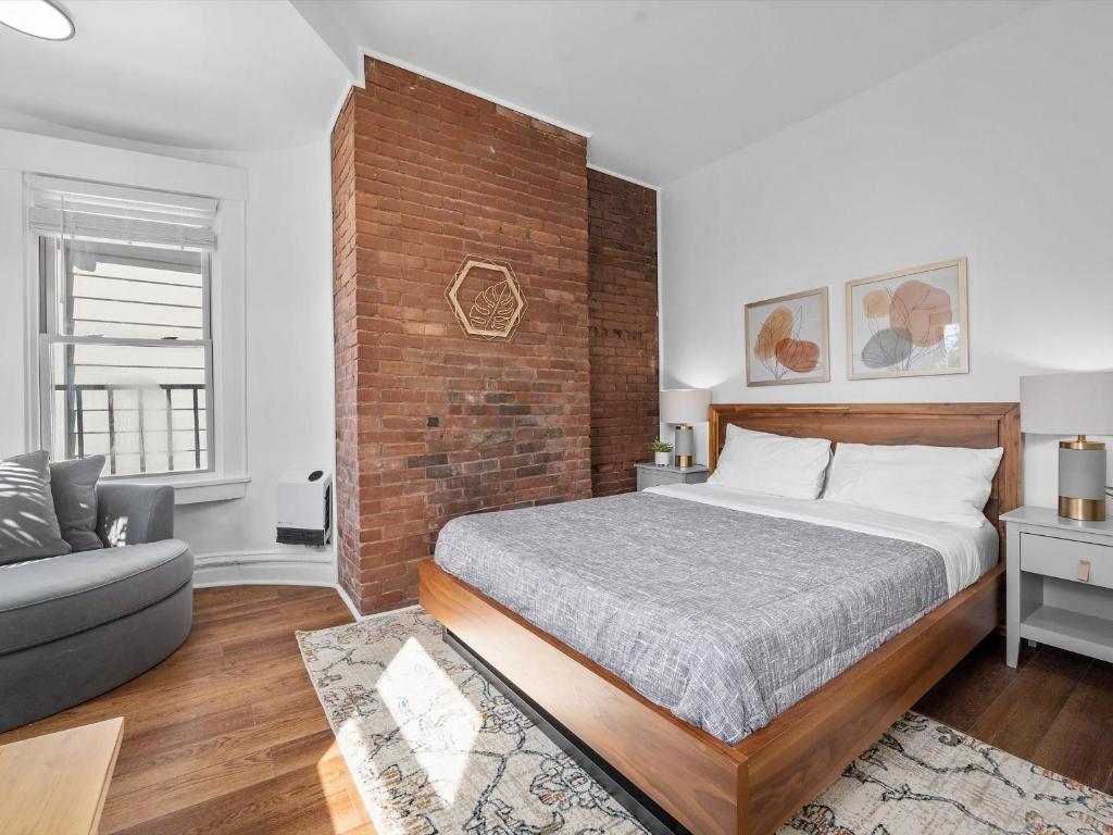1 dormitorio con cama y pared de ladrillo en Shadyside, Pittsburgh, Modern and Bright 1 Bedroom Unit4 with Free Parking en Pittsburgh