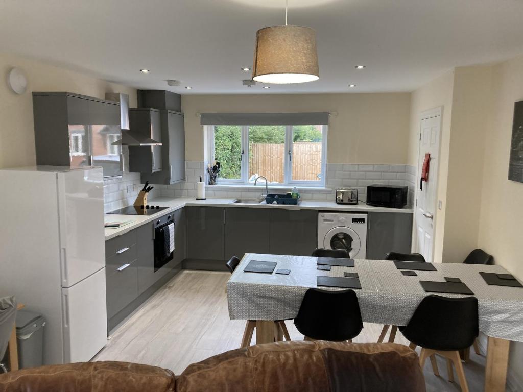 a kitchen with a table and chairs in a room at Newly built 3 Bed House with Ample Parking 2 in Balderton