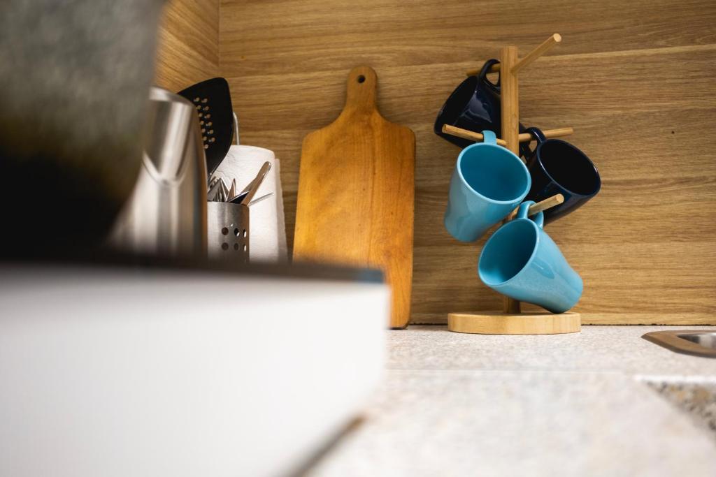 a kitchen counter with blue mugs and a wooden rack at Capsule Hostel Logistic Vilnius in Vilnius