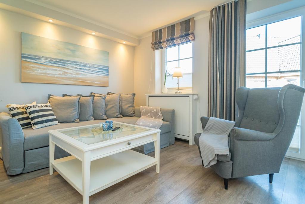 a living room with a couch and a table and a chair at Appartement Lachmöwe - Nicolinenhof in Wenningstedt
