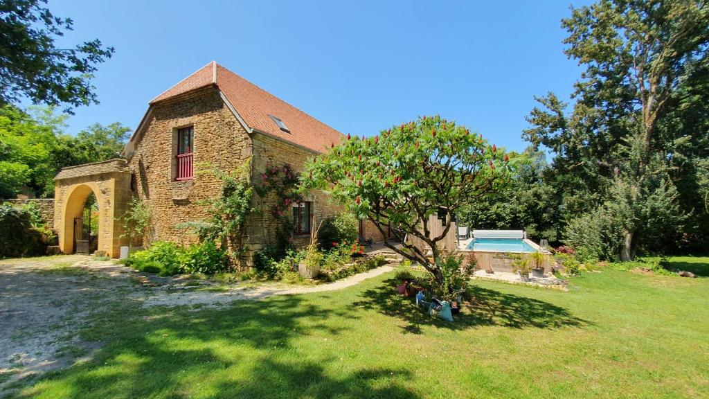 una vieja casa de ladrillo con un árbol en el patio en Le Clos d'Ô Les Rapiettes maison proche Sarlat avec piscine privée, en Prats-de-Carlux
