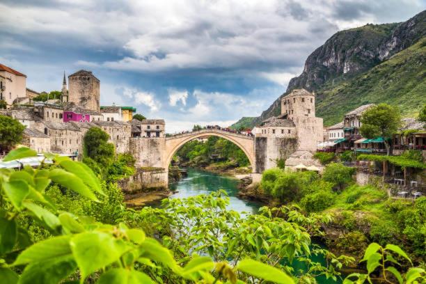 a bridge over a river next to a mountain at Lovely Bosnian Home in Mostar
