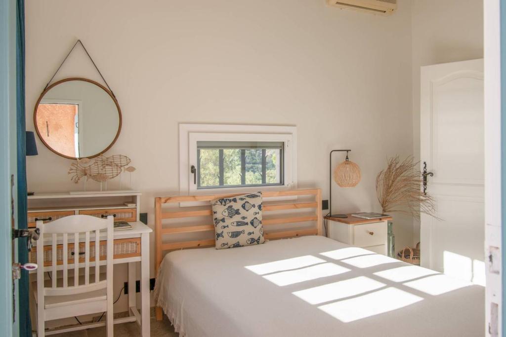 1 dormitorio con cama y espejo en La Villa Là-bas, en Rayol-Canadel-sur-Mer