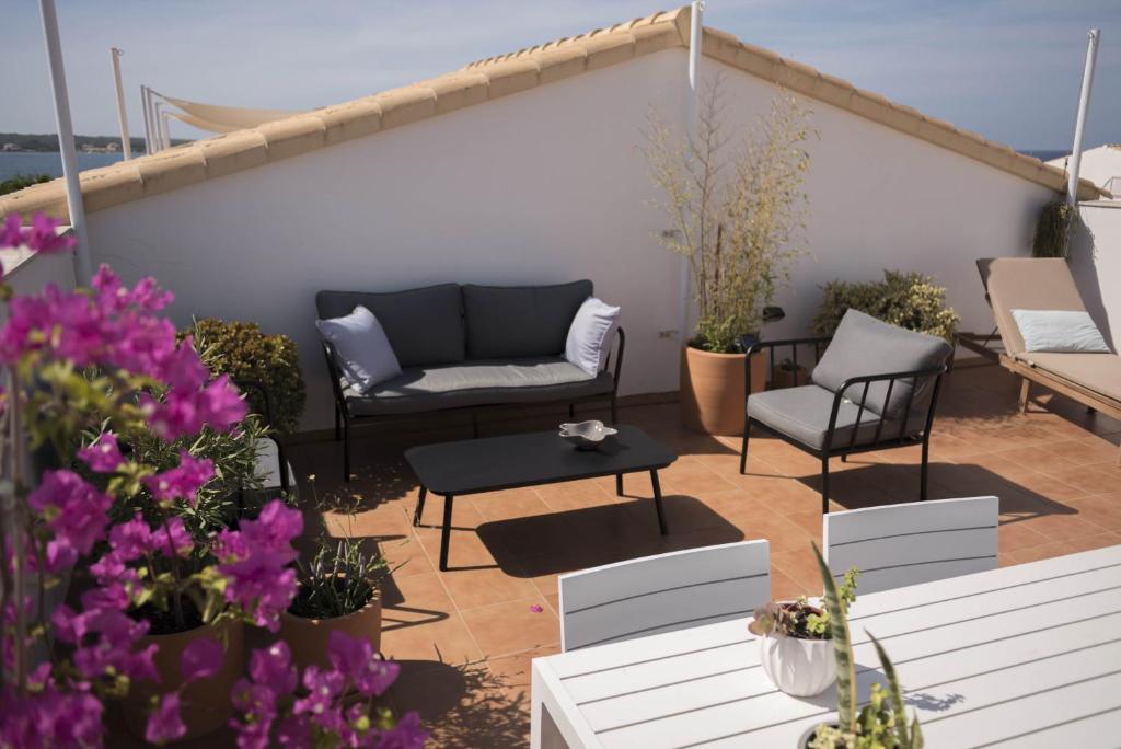 a patio with a couch and chairs and flowers at Edificio can Sord Apto nº 2 in La Savina