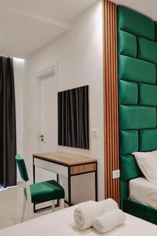 a bedroom with a desk and a green chair at Vila Shpetimi in Ksamil