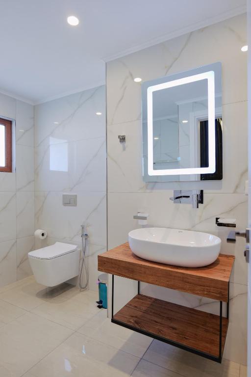 a white bathroom with a sink and a mirror at Vila Shpetimi in Ksamil