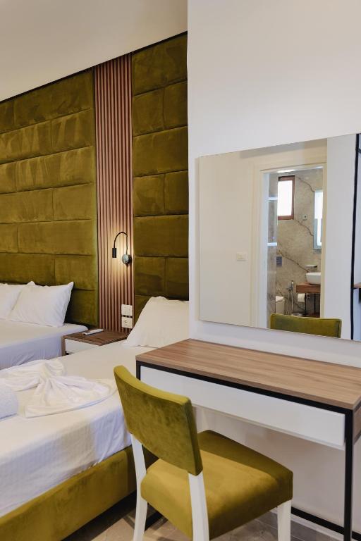 a bedroom with two beds and a desk and a chair at Vila Shpetimi in Ksamil
