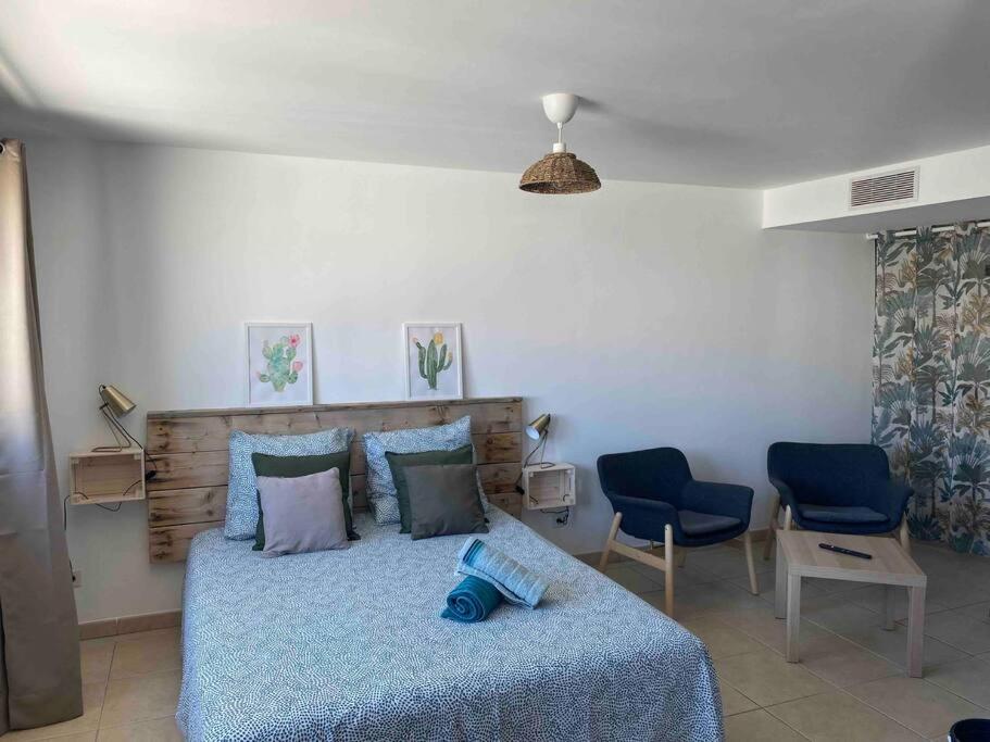 une chambre avec un lit et deux chaises bleues dans l'établissement Studio Benvengudo Port La Ciotat - Appartement et parking, à La Ciotat