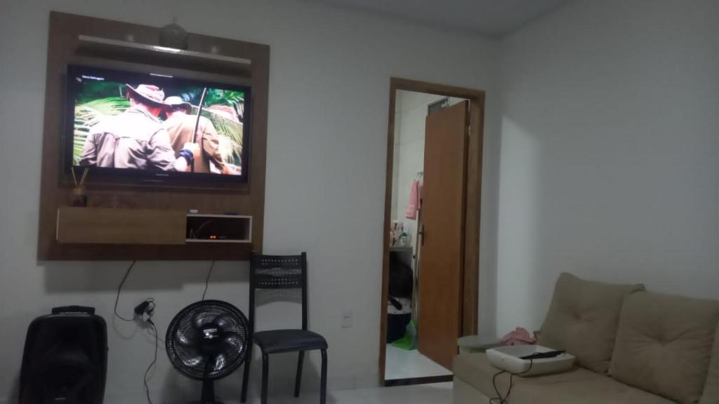 sala de estar con sofá y TV en la pared en Casa para alugar ano novo, en Itacaré