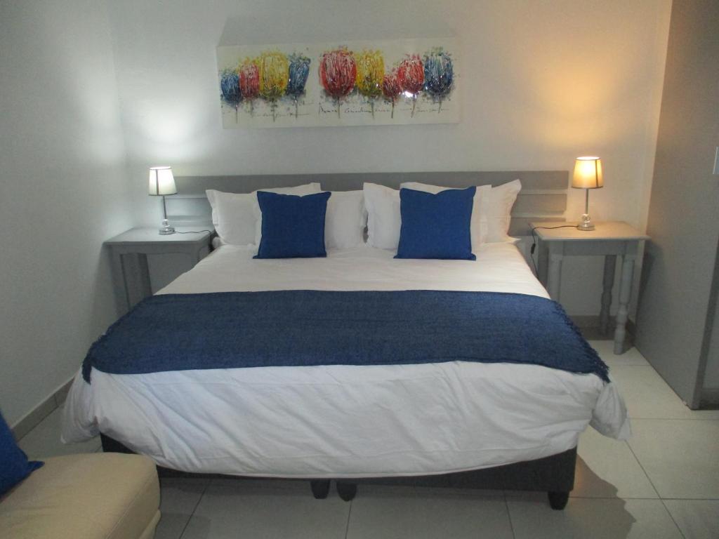 a bedroom with a large bed with blue and white pillows at LEKKER RUS in Bloemfontein