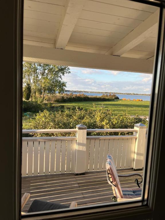 une personne assise sur une terrasse couverte donnant sur une fenêtre dans l'établissement Villa Wiegand - a room with a view, à Holbæk