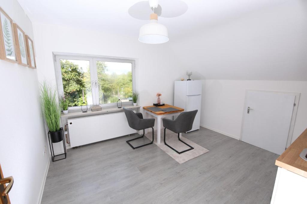 Biały pokój ze stołem i krzesłami oraz oknem w obiekcie NATURBLICK Apartments 2 Moderne Ferienwohnung w mieście Grebenhain