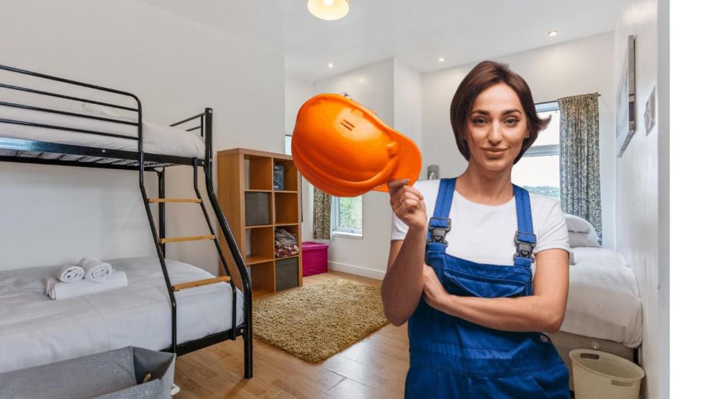 a woman holding up a pumpkin in a bedroom at Contractors & Pets Welcome - Sleeps 1-4, less than 1 mile from M606, Ideal for Longer Stays in Cleckheaton