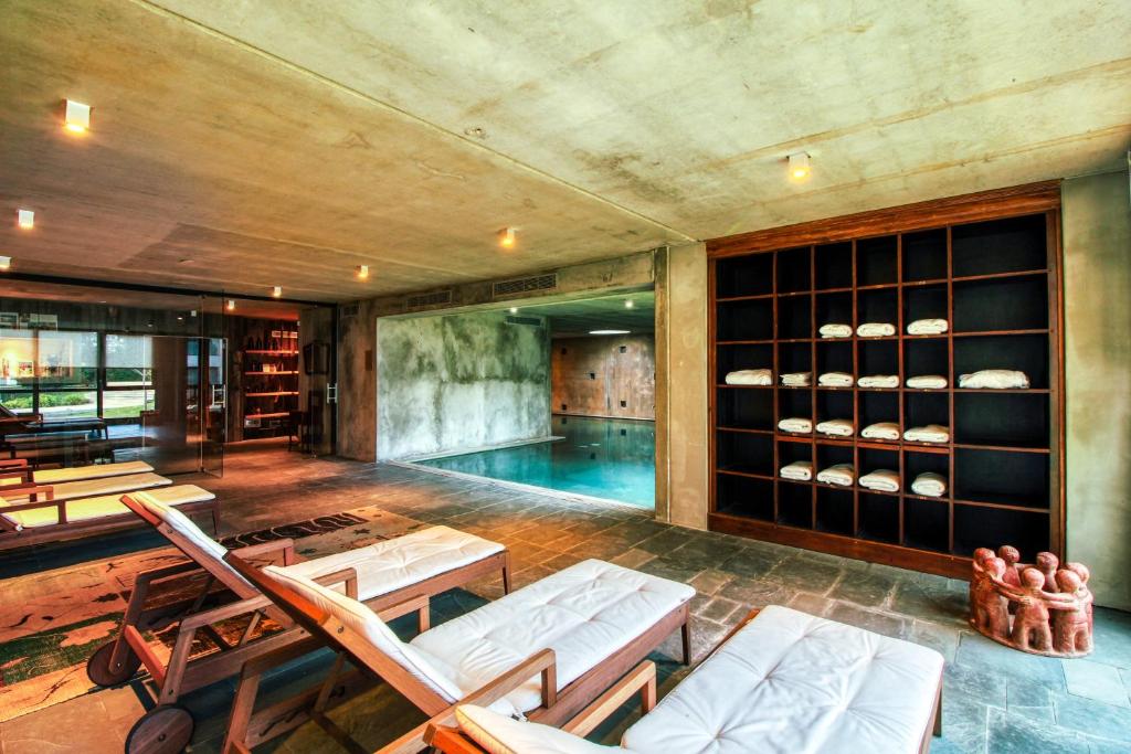 een woonkamer met een zwembad en stoelen en een zwembad bij Be House & Spa by Oceana Suites in Punta del Este