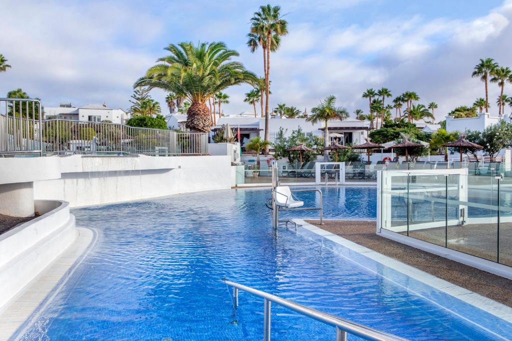 a swimming pool at a resort with palm trees at Jardines del Sol in Playa Blanca