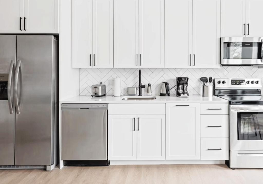 Una cocina con gabinetes blancos y electrodomésticos de acero inoxidable. en Award Rentals, en Washington