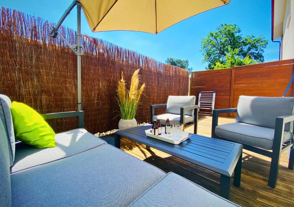 un patio avec deux chaises, une table et un parasol dans l'établissement Les Oyats - Central et spacieux, à Biscarrosse