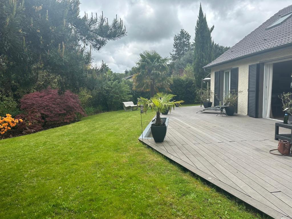 une terrasse en bois avec des plantes dans une cour dans l'établissement Villa JO 2024, à Buc