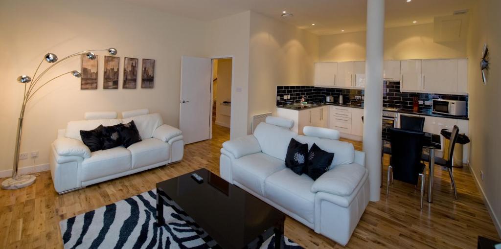 a living room with two white couches and a kitchen at Trinity Quay Apartments in Aberdeen