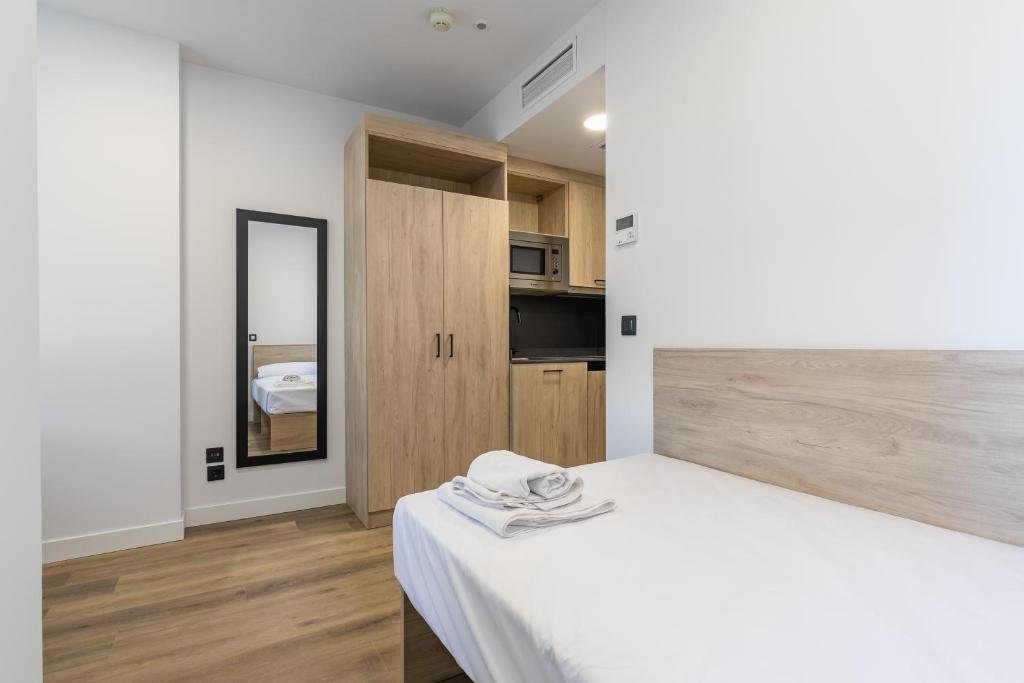 1 dormitorio con cama blanca y espejo en Micampus Wynwood - Xaudaro, en Madrid