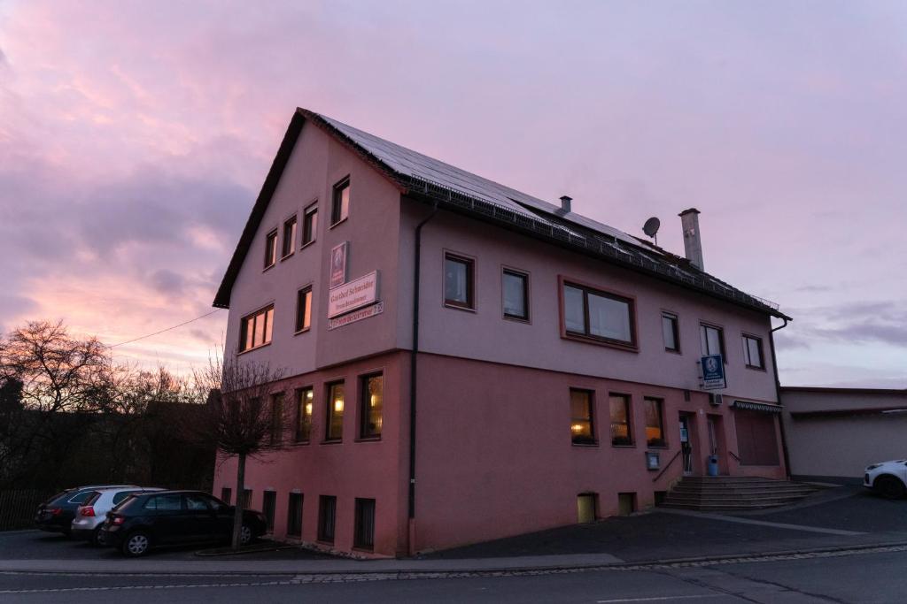duży czerwony budynek z zachodem słońca w tle w obiekcie Gasthaus Schneider w mieście Bad Bocklet