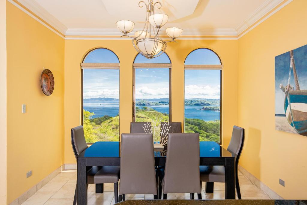 een eetkamer met een tafel, stoelen en ramen bij Casa Q - Bella Vista in Playa Hermosa