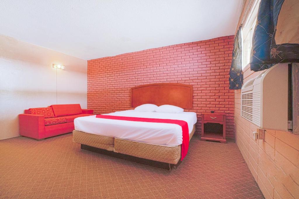 a bedroom with a bed and a red couch at Town & Country Motel Bossier City by OYO in Bossier City