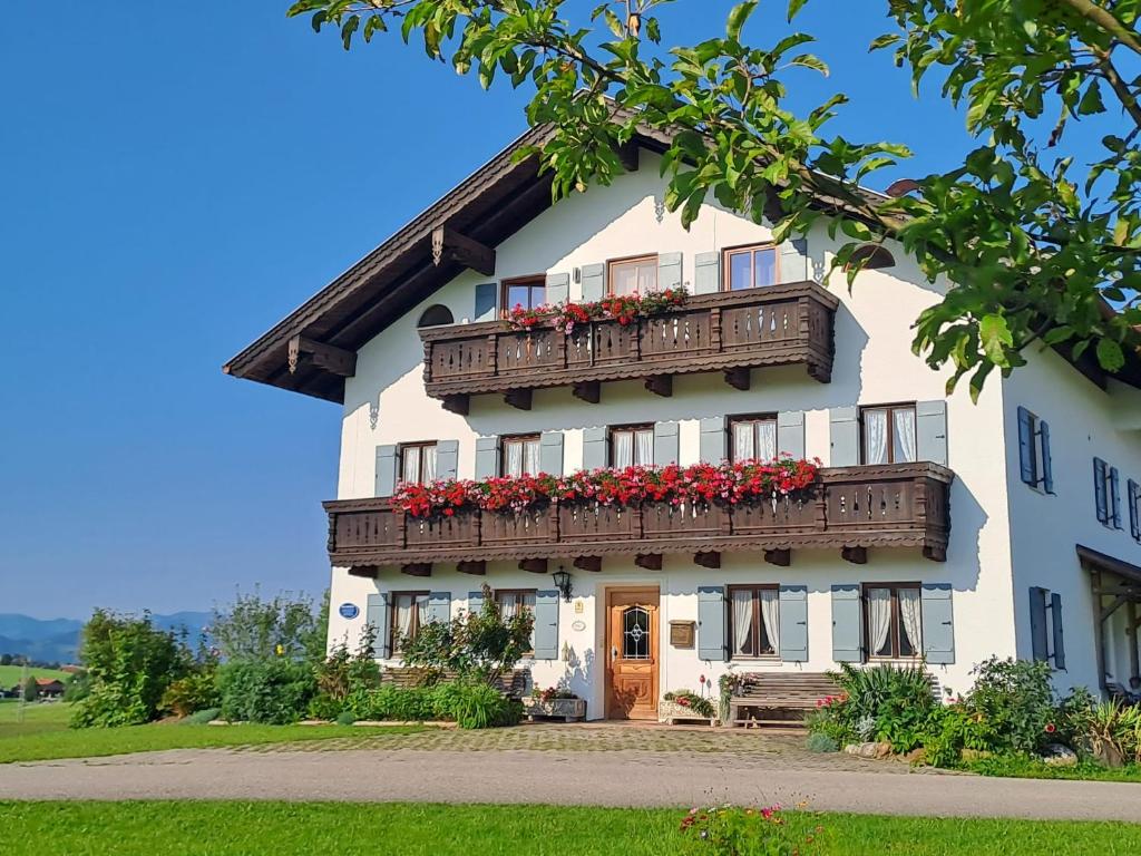 a white building with a balcony with red flowers at Asbichlerhof in Bad Endorf