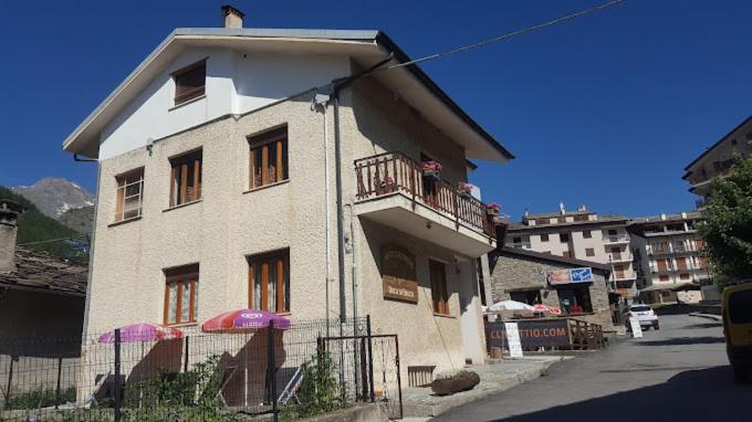 a small white house with a balcony on a street at Affittacamere Buca di bacco in Pontechianale