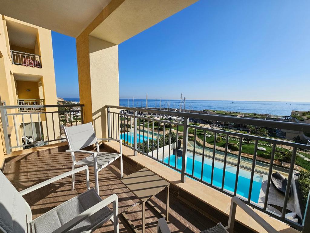 a balcony with a view of a pool and the ocean at Stunning Seafront Portomaso Apartment in Paceville