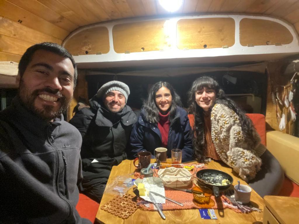 grupa ludzi siedzących przy stole w obiekcie Camperbus Apawata w mieście Puerto Natales