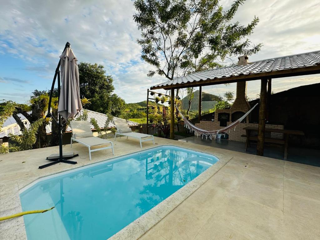 uma piscina com rede e guarda-sol em Chacara em Ubatiba-Maricá em Maricá