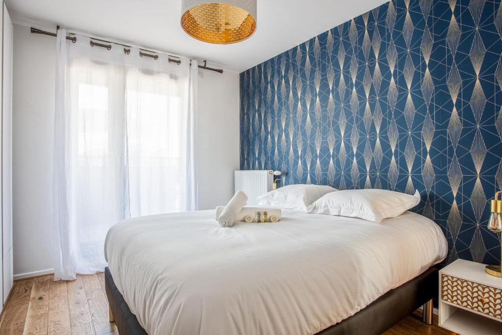 a bedroom with a large bed with a blue wall at Comfortable flat w views of Paris in Saint-Denis - Welkeys in Saint-Denis