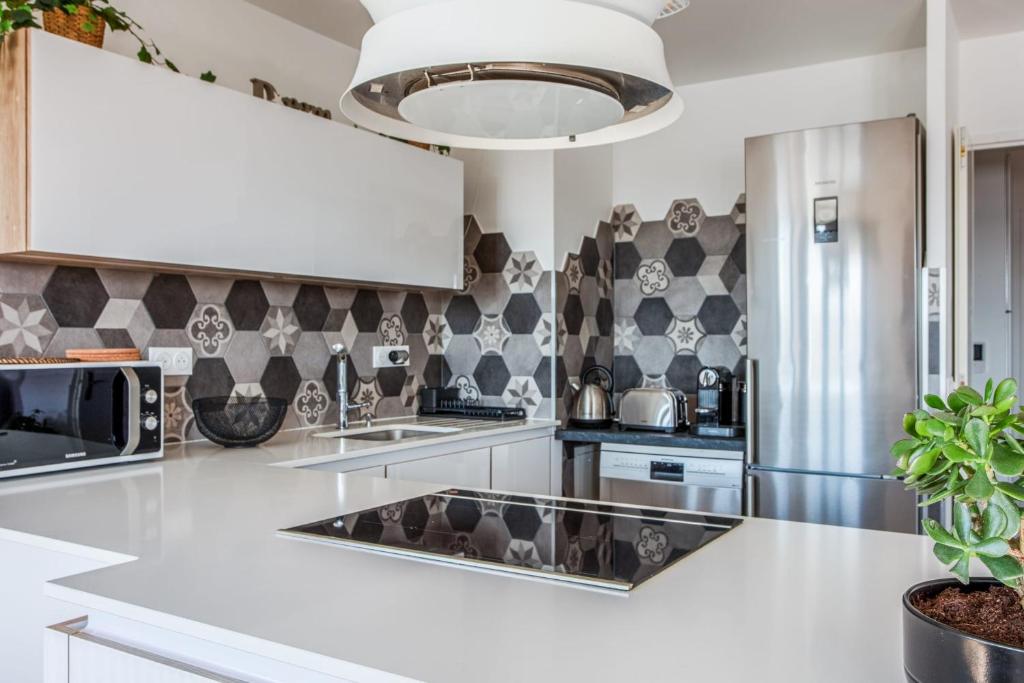 a kitchen with white countertops and a black and white wallpaper at Comfortable flat w views of Paris in Saint-Denis - Welkeys in Saint-Denis