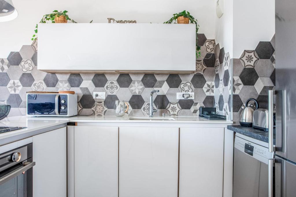 a kitchen with white cabinets and a tile wall at Comfortable flat w views of Paris in Saint-Denis - Welkeys in Saint-Denis