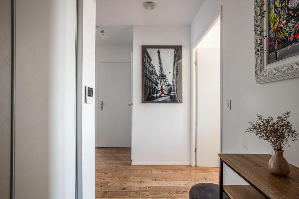 a hallway with white walls and a table and a picture on the wall at Comfortable flat w views of Paris in Saint-Denis - Welkeys in Saint-Denis