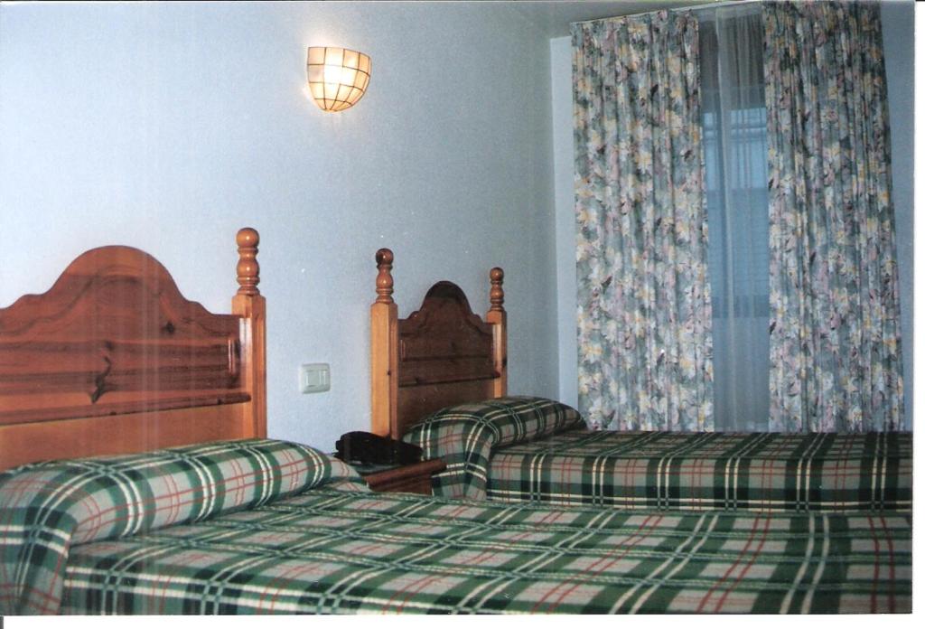 a hotel room with two beds and a lamp at Hostal Niza in Badajoz