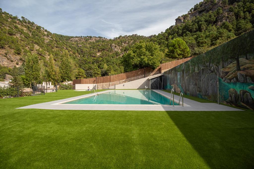 a swimming pool in a grass field with a mural at Apartamentos 7 Puentes Sierra Cazorla Las 5 casas iguales in Burunchel
