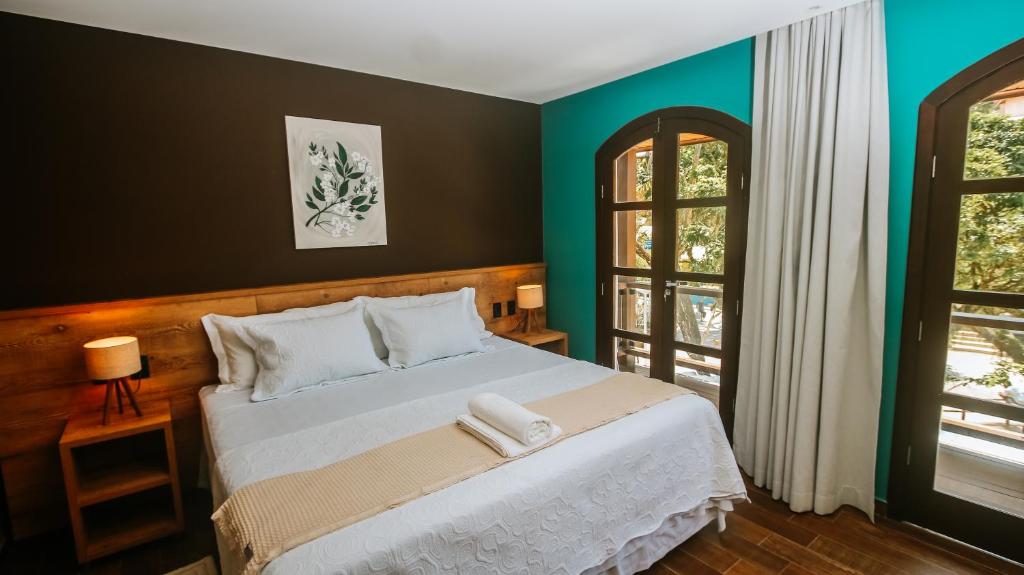 ein Schlafzimmer mit einem großen weißen Bett mit grünen Wänden in der Unterkunft Flores da Praça in Morro de São Paulo