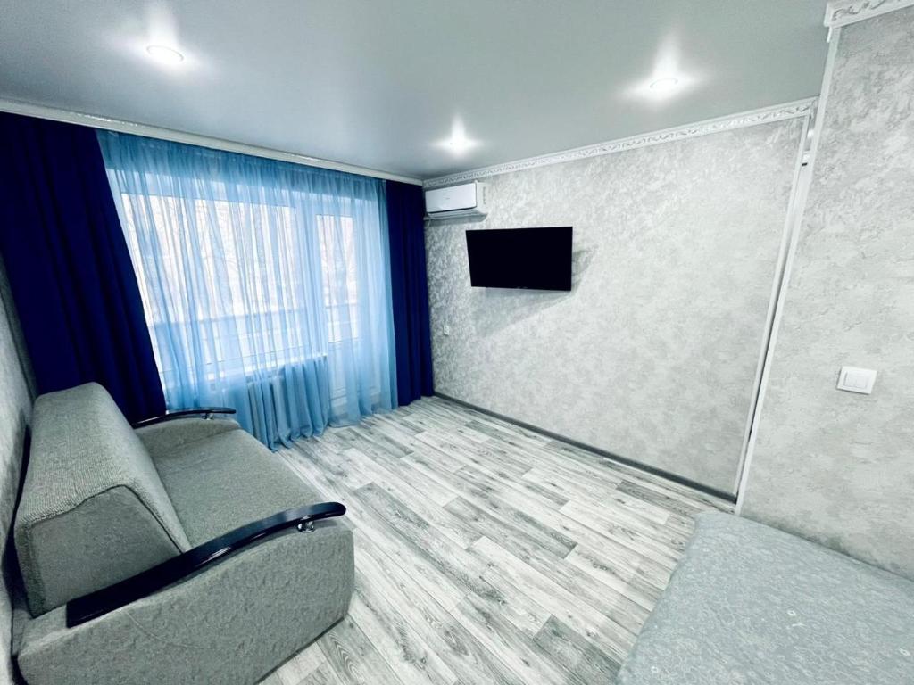 Habitación con sofá y TV de pantalla plana. en 1 комнатная квартира посуточно, en Uralsk