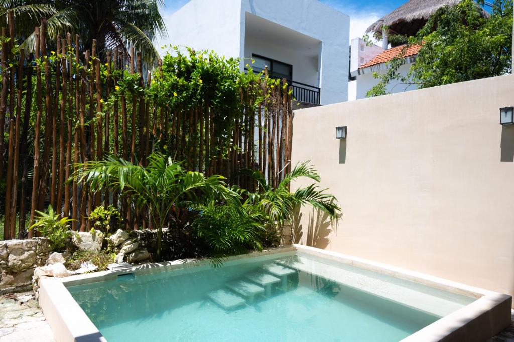 a swimming pool in front of a house with a fence at Yax Kiin Casa Boutique in Puerto Morelos