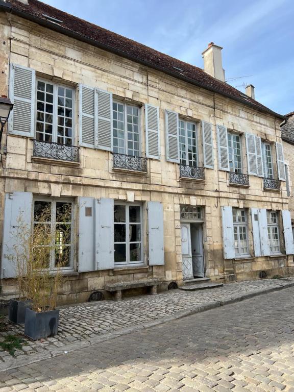 ein altes Gebäude mit weißen Türen und Fenstern in der Unterkunft QUELQUES JOURS À NOYERS SUR SEREIN in Noyers-sur-Serein