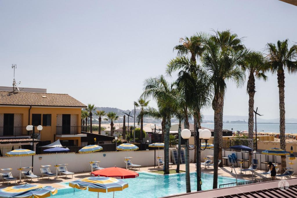 uma vista para uma piscina com palmeiras e cadeiras em Andrea Case Vacanze L'Ancora em Porto Empedocle
