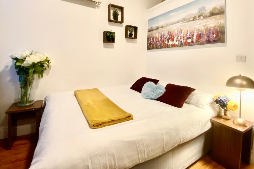a bedroom with a white bed with a yellow blanket on it at NewDay Property - Golders Green in London