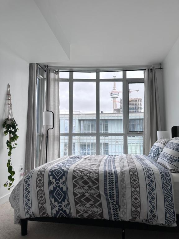 a bedroom with a bed and a large window at Stylish 2 Bedrooms Condo w/ awesome View & Parking in Toronto
